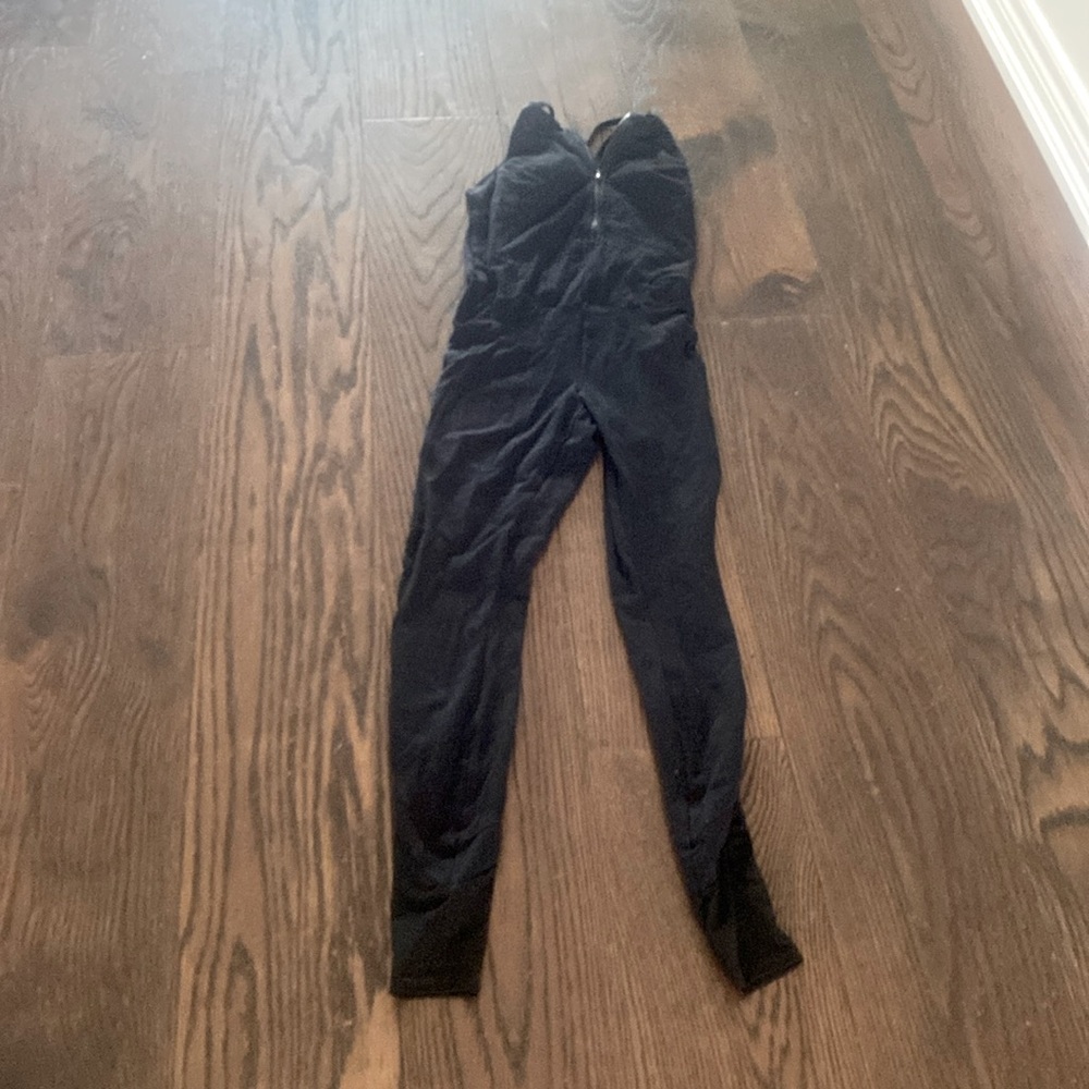 Black cross back jumpsuit with mesh paneling on legs.